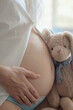 © Leka - Close-up woman pregnant belly with teddy toy, Concept of maternity,  expect for baby. Happy expectant mother during pregnancy.