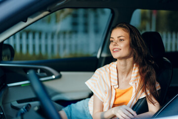 Wall Mural - Young woman sitting in a car smiling, casual outfit, sunlight streaming through the window, relaxed ambiance, car interior in soft colors, summertime vibes and joyfulness