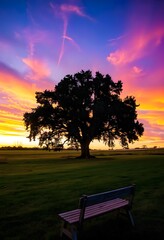 Wall Mural - Solitary tree standing tall in a vast green field, with a vibrant sunset in the background.