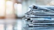 © Sinechana - 129. Pile of newspapers with visible headlines and articles, set against a blurred background to draw focus on the stack