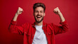 © Synthesia Studio - Excited young man in red shirt celebrating with raised fists against red background