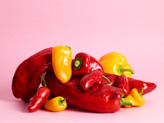 Pile of bell and long sweet peppers over pink background