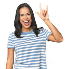 Wall Mural - young latina posing in studio showing a horns gesture as a revolution concept.