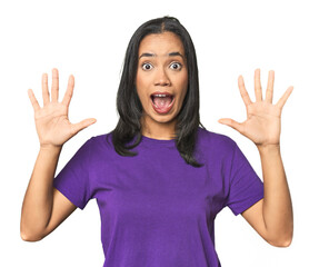 Wall Mural - young latina posing in studio receiving a pleasant surprise, excited and raising hands.