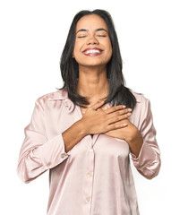 Wall Mural - simple portrait of a young latina laughing keeping hands on heart, concept of happiness.