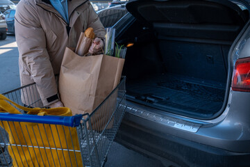 Man Loading Groceries into Car Trunk