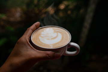  hand people is holding an aromatic latte art coffee cup. Drink coffee by the window.  dark of vignette Selective focus