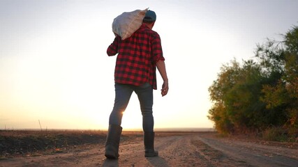 Sticker - farmer working with sack in agricultural field lifestyle. agriculture a business farm concept. farmer worker carries a bag with harvest at sunset silhouette in agricultural field