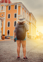 Travel woman in a tourist square at sunset, Granada, Nicaragua. Back view of tourist girl walking in a tourist square