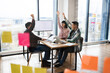 © sofiko14 - Meeting of architects in office celebrating success. Group discussion on project with raised hands expressing excitement and teamwork. Workspace with large windows, computer screen, sticky notes.