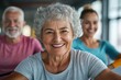 © Milos - A smiling elderly woman with curly hair is happily posing with friends at a fitness center, reflecting the joy of an active lifestyle and sociable engagement.