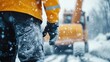 © Maximages  - A close-up of a construction worker's lower body, showing protective wear during work in snowy conditions, symbolizing dedication and hard work against harsh weather.