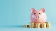© Tendo - cute pink piggy bank with a stack of gold coins on a light blue background. Concept of saving money.