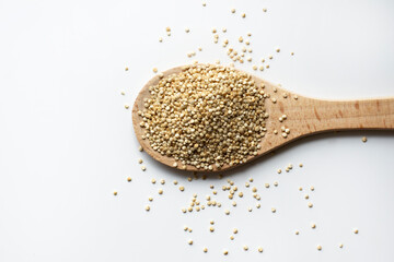 quinoa in the wooden spoon with seeds on white surface. Copy space