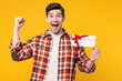 © ViDi Studio - Young happy man he wears red checkered shirt casual clothes hold gift certificate coupon voucher card for store do winner gesture isolated on plain yellow orange background studio. Lifestyle concept.
