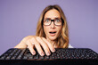 © ViDi Studio - Close up young sad shocked surprised amazed employee business woman corporate lawyer wear glasses work in office typing on pc computer keyboard, look camera isolated on plain purple background studio.