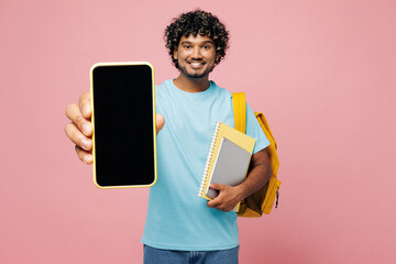 Sticker - Young smart Indian boy student wears blue t-shirt casual clothes backpack bag hold books use blank screen mobile cell phone isolated on plain pink background. High school university college concept.