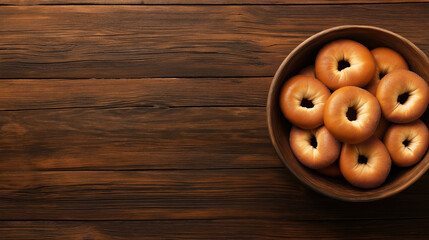 Poster - A wooden bowl filled with plain bagels sits on a dark wooden table. The bagels have a smooth, golden-brown crust and are neatly arranged inside the bowl.