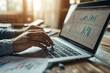 © syhin_stas - Businesswoman deeply analyzing financial charts on her laptop in the office, focusing on data with a pen in hand, showcasing dedication to finance and market trends