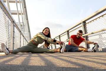 Couple of two friends exercise and stretch before jogging on the bridge