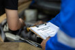 © Wasan - Automobile mechanic repairman checking a car engine with inspecting writing to the clipboard the checklist for repair machine, car service and maintenance.