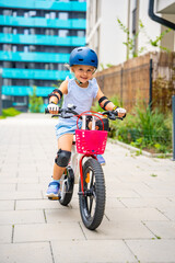 Little girl rides a two-wheeled bicycle Ii the courtyard of apartment buildings in summer, Europe