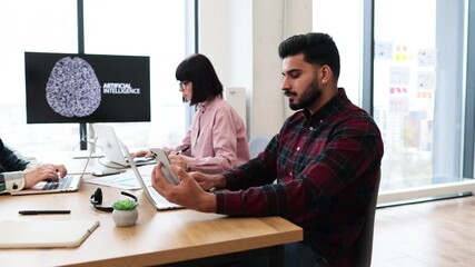 Team of IT experts collaborating on developments of artificial intelligence in office. Professionals working on laptops and mobile devices. Concept of teamwork technology innovation in workplace