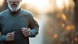 © Maximages  - A person wearing a gray athletic jacket jogs through a serene nature path during a golden sunrise, promoting a healthy and active lifestyle in the beauty of early morning light.