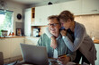 © Davor - Happy mature couple using credit card on laptop at home