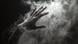 © CinimaticWorks - dramatic silhouette of a human hand in the smoke emerging from the dark background creating a mysterious and moody scene