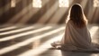 © Maximages  - A person wrapped in a white shawl is seated, appearing to meditate under beams of natural light streaming into a tranquil, serene spacious room, embracing peace and introspection.