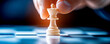 © HDP-STUDIO - A close-up of a hand moving a white chess piece on a blue chessboard, symbolizing strategy and decision-making in the game.