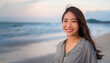 © ณัฐพล ตีระพิมลจันทร์ - beautiful woman with a radiant smile, standing on a serene beach. The warm sunset and soft sand create a peaceful and joyful atmosphere, travel, happiness, summer vacations, lifestyle, wellness