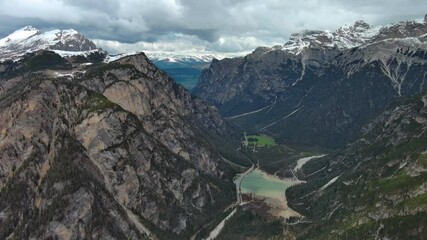 Wall Mural - Aerial view of amazing rocky mountains valley in snow under moody gray clouds, Dolomites, Italy, 4k