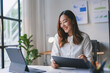 © amnaj - Businesswoman smiling and working on documents at desk
