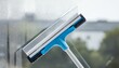 © TransPicHub - A blue squeegee cleaning a window, showcasing a streak-free shine and modern cleaning tools for home or commercial use.