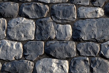 A textured stone wall made of large, irregularly shaped gray stones. The stones have a rough surface with visible cracks and variations in color, creating a natural and rustic appearance.