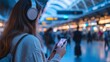 © The Origin 33 - Woman Listening to Music on Headphones While Using Smartphone in Train Station