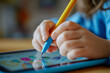© kashiStock - a child’s hand drawing on a tablet with a stylus, with educational content displayed on the screen