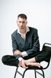 © Elina Leonova - Handsome man, fashion model sits on chair barefoot
