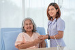 © surachetkhamsuk - Asian female home nursing holding hand of older lady on the bed and encouraging patient