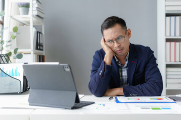 Wall Mural - Stressed asian businessman having problem working with digital tablet in office