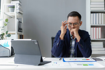 Wall Mural - Stressed asian businessman touching his head while working