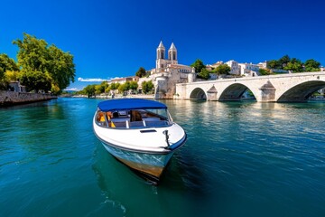 A boat tour gliding down the RhÃ´ne River, with the city of Avignon slowly coming into view, framed by the bridge and towering cathedral