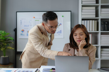 Wall Mural - Asian businessman explaining work to female intern at office