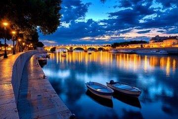 A sunset view of the RhÃ´ne River, with the lights of Avignon reflecting on the water as boats drift lazily by