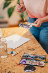 Wall Mural - Close up of creative painter's hands mixing paint on palette at atelier