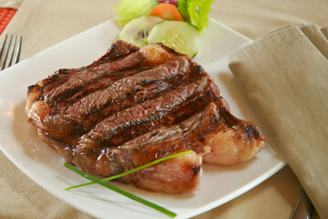 Grilled steak with vegetables resting on a white plate