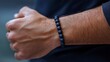 © Petzhy - A mans wrist adorned with matte black stone bracelet showcases stylish accessory that adds touch of elegance to any outfit. bracelets unique texture and design enhance its appeal.