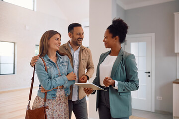 Wall Mural - Happy couple and real estate agent using digital tablet during open house day.